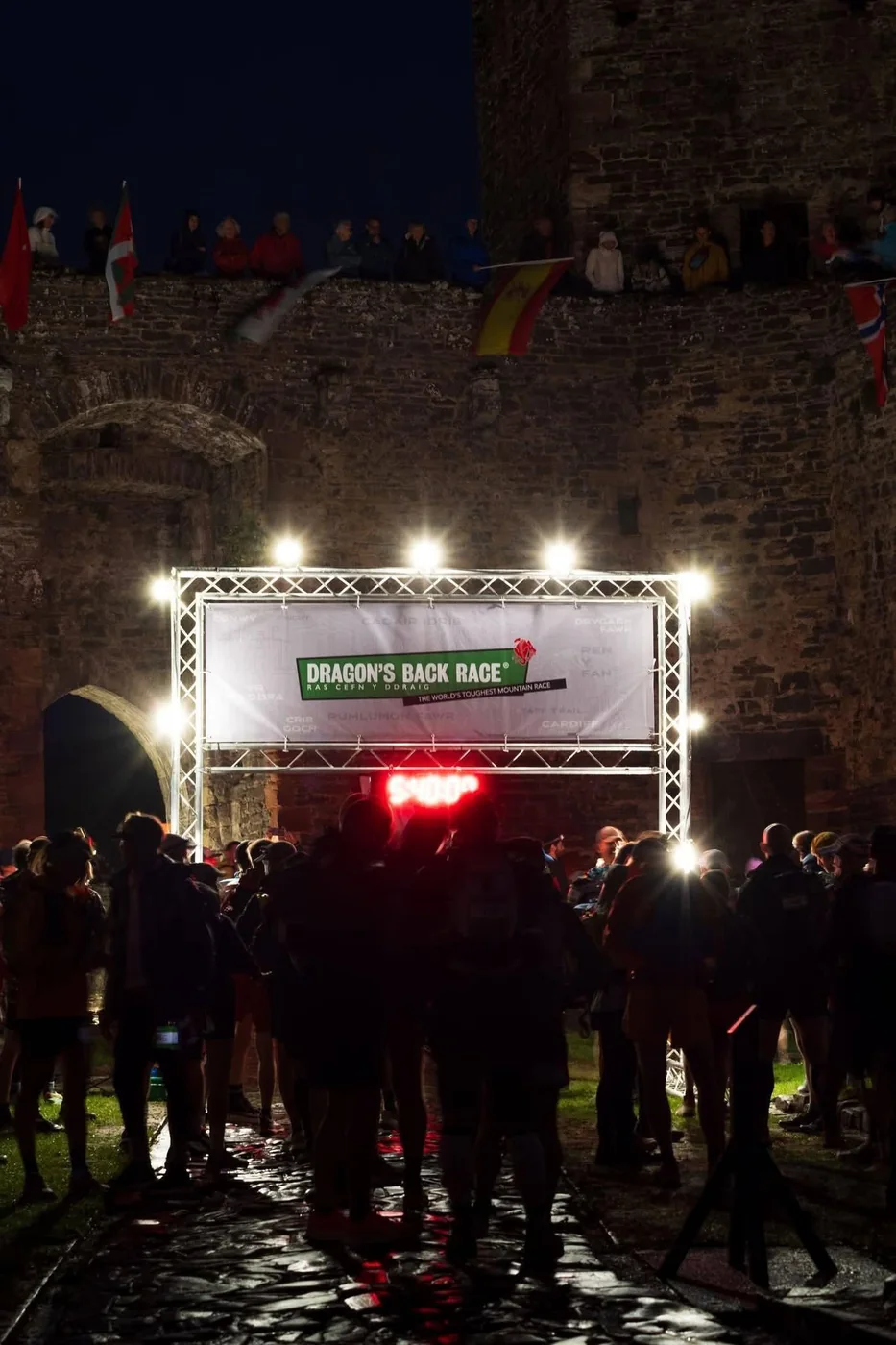 The lit start gantry inside Conwy Castle before dawn, with spectators watching from the castle walls
