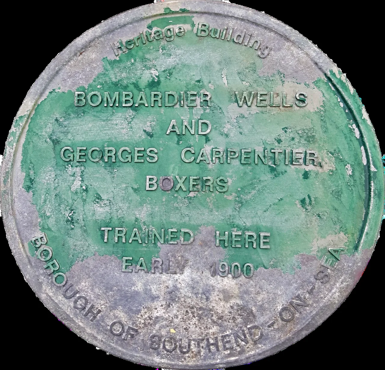 The original Wells and Carpentier plaque, green paint flaking over bare metal, with the same wording as the new one